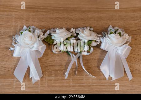 Élégantes boutonnières florales blanches avec des rubans de satin sur fond en bois. Banque D'Images