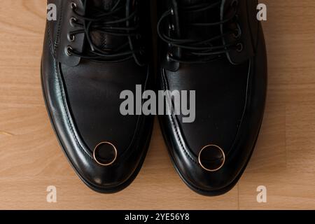 Chaussures élégantes en cuir noir avec anneaux de mariage sur les conseils. Banque D'Images