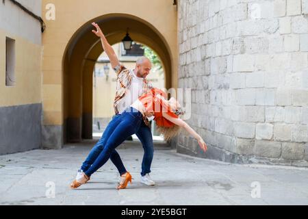 Un couple effectue une routine de danse énergique dans une ruelle étroite, avec l'homme soutenant la femme dans un plongeon dramatique, soulignant leur passion et SK Banque D'Images