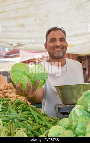 Vendeur montrant à caméra différents légumes sur sa main dans le marché de rue Inde à Jodhpur, Inde. Banque D'Images