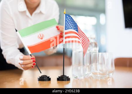 Drapeaux nationaux de l'Iran et des États-Unis entre les mains d'une employée de bureau Banque D'Images