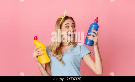 Rire fille choisit une bouteille de fournitures de nettoyage Banque D'Images