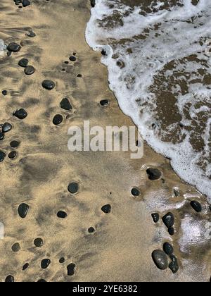 Mousse d'eau de mer sur le rivage avec du sable et des galets. Fond d'écran abstrait Seascape avec espace de copie. Banque D'Images