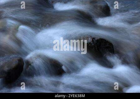 Environnement. L'eau cristalline à écoulement rapide coule par des roches dans un grand ruisseau. Jamor River. Oeiras, Portugal. Techniques photographiques, exposition longue Banque D'Images