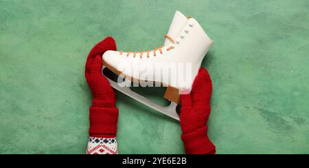 Mains féminines avec patins à glace sur fond vert Banque D'Images