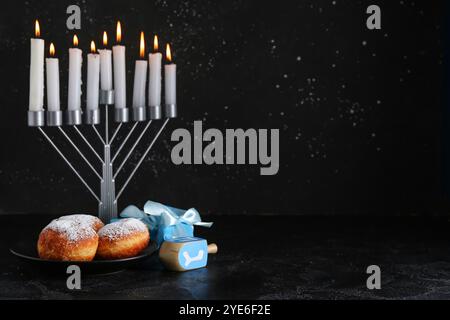Menorah, beignets savoureux et cadeaux pour la célébration Hanukkah sur fond sombre Banque D'Images