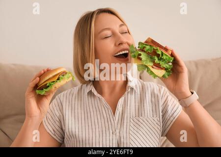 Belle femme avec de la nourriture malsaine à la maison, gros plan. Concept de suralimentation Banque D'Images