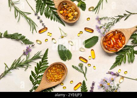 Composition avec des cuillères en bois de pilules et différentes herbes sur fond clair Banque D'Images