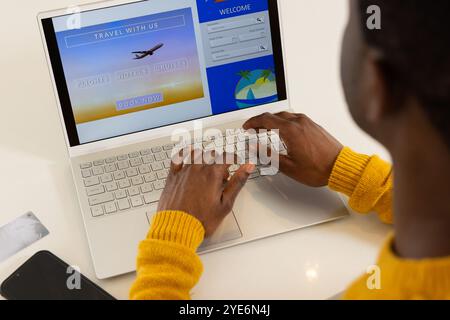 Réservation de voyage de vacances en ligne, homme afro-américain utilisant un ordinateur portable à la maison, planification de vacances Banque D'Images