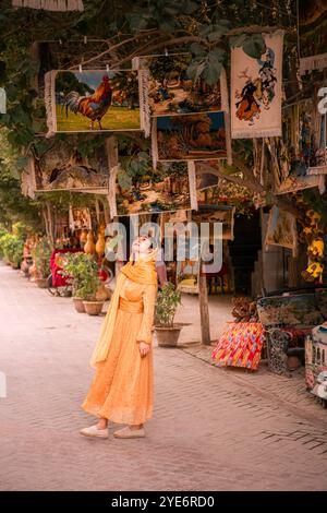 Kashgar, Chine - 17 JUILLET 2022 : une fille à côté du magasin vendant des tapis et des instruments de musique dans la rue de la ville antique de Kashgar, Xinjiang, Chine Banque D'Images