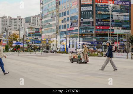 L'homme marche sur le trottoir. Une femme pousse un chariot Banque D'Images