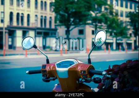 Cyclomoteur scooter rouge garé dans une rue de ville reflétant le ciel dans les miroirs. Banque D'Images