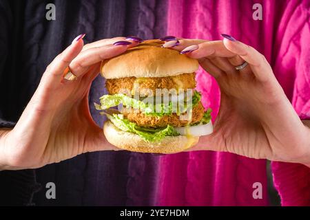 Femme tenant un hamburger de poisson ou de poulet avec les deux mains Banque D'Images