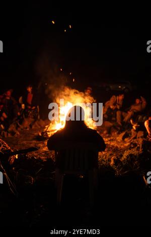 Silhouette de l'homme devant un feu de camp avec des gens la nuit Banque D'Images