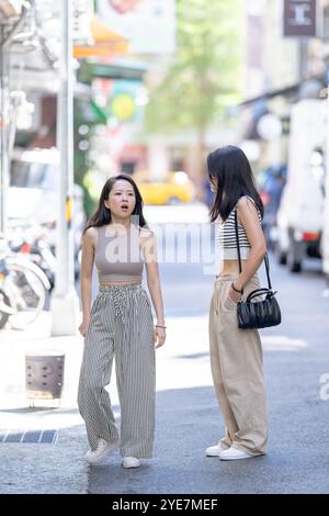 Deux femmes taïwanaises dans les années 30 portant des tenues décontractées marchent le long de la rue Dihua dans la ville de Taipei, Taiwan, en septembre. Banque D'Images