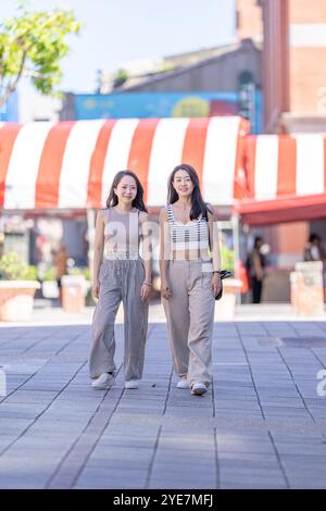 Deux femmes taïwanaises dans les années 30 portant des tenues décontractées marchent le long de la rue Dihua dans la ville de Taipei, Taiwan, en septembre. Banque D'Images