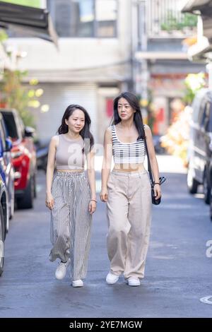 Deux femmes taïwanaises dans les années 30 portant des tenues décontractées marchent le long de la rue Dihua dans la ville de Taipei, Taiwan, en septembre. Banque D'Images