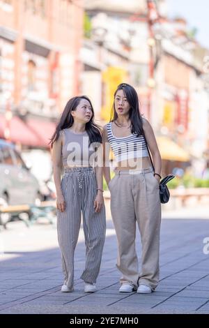 Deux femmes taïwanaises dans les années 30 portant des tenues décontractées marchent le long de la rue Dihua dans la ville de Taipei, Taiwan, en septembre. Banque D'Images