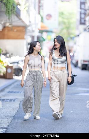 Deux femmes taïwanaises dans les années 30 portant des tenues décontractées marchent le long de la rue Dihua dans la ville de Taipei, Taiwan, en septembre. Banque D'Images