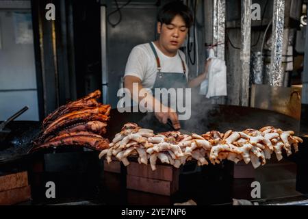 Homme coréen cuisinant du calmar et du poulpe sur le marché de la nourriture de rue à Jeju, Corée du Sud Banque D'Images