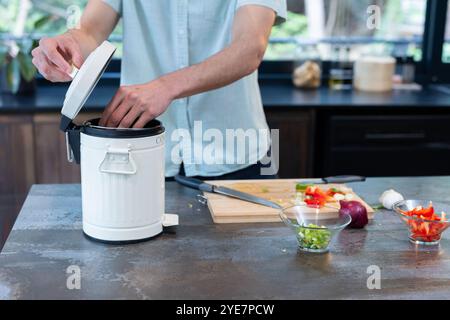 Compostage des déchets de légumes, homme dans la cuisine favorisant un mode de vie écologique, à la maison Banque D'Images