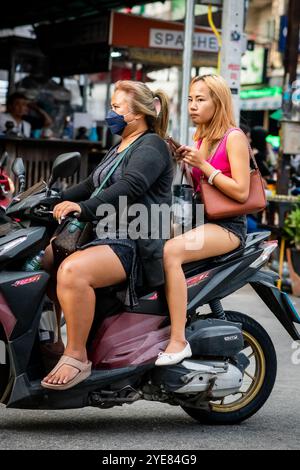 Deux filles thaïlandaises font leur chemin le long de soi Buakhao, Pattaya, Thaïlande sur leur scooter. Banque D'Images