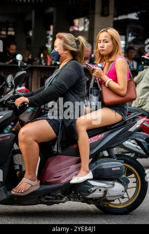 Deux filles thaïlandaises font leur chemin le long de soi Buakhao, Pattaya, Thaïlande sur leur scooter. Banque D'Images