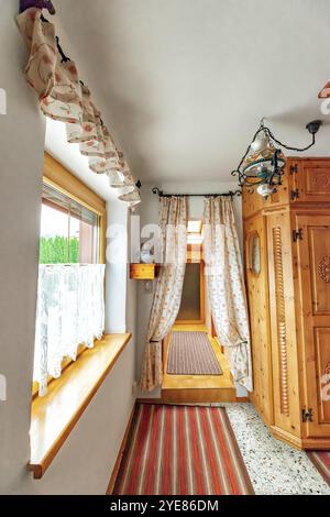 Intérieur de maison ancienne confortable avec couloir, tapis rayé sur le sol, plafonnier et grande armoire en bois vintage Banque D'Images