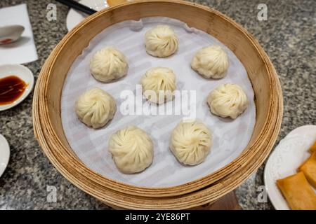 Dim sum cuit dans une marmite à vapeur en bambou servi dans un restaurant asiatique. Boulettes avec shumai dim sum, cuisine chinoise. Boulettes chaudes cuites à la vapeur avec végétab Banque D'Images