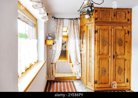 Intérieur de vieille maison avec couloir, tapis rayé au sol, plafonnier, vase pot sur étagère et grande armoire en bois vintage Banque D'Images