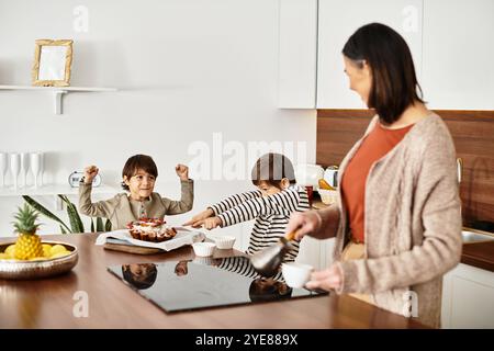 Une famille heureuse prépare des friandises festives dans une cuisine contemporaine, les enfants aidant joyeusement dans le processus. Banque D'Images