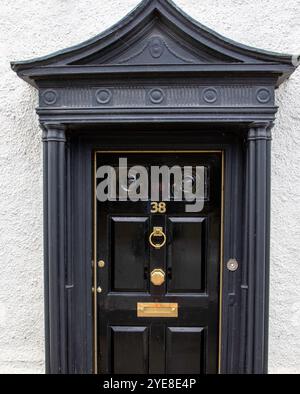 Porte d'entrée d'époque élégante dans une ville de Suffolk fraîchement peinte noir brillant et avec des raccords en laiton, y compris un frappeur de porte, boîte aux lettres et 38. Banque D'Images