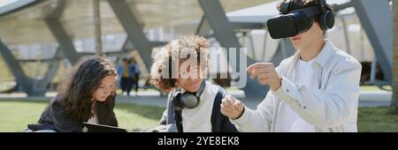 Bannière de site Web d'amis d'école multiraciaux s'amusant avec des appareils électroniques dans le parc Banque D'Images