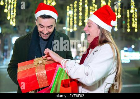 Couple excité échangeant des cadeaux de Noël à l'extérieur Banque D'Images