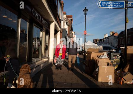 Un couple se promène le long de Lymington High Street, parmi les boîtes et les ordures laissées sur les étals du marché du samedi, Hampshire, Angleterre, Royaume-Uni Banque D'Images