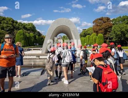 Groupe d'écoliers japonais regardant à travers le cénotaphe commémoratif des victimes d'Hiroshima jusqu'au dôme de la bombe atomique, à Hiroshima, Japon le 29 Septembe Banque D'Images