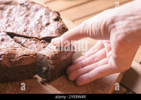 Main prendre un morceau de gâteau au brownie au chocolat fraîchement cuit Banque D'Images