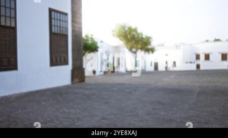 Scène extérieure floue à lanzarote, en espagne avec des bâtiments blancs, un pavé pavé et des arbres défocalisés dans les îles canaries. Banque D'Images