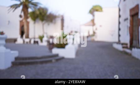 Scène extérieure floue à lanzarote, en espagne, avec des bâtiments blancs défocalisés avec des palmiers et un chemin pavé dans les îles canaries. Banque D'Images