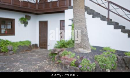 Scène extérieure floue à lanzarote, en espagne avec un arrière-plan flou, y compris un arbre, des plantes et un bâtiment blanc traditionnel avec des portes en bois et Banque D'Images