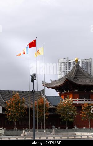 Drapeau national chinois et autres drapeaux agitant sur des mâts de drapeau devant l'architecture chinoise traditionnelle Banque D'Images