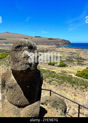 Statue de moai solitaire à la carrière de Rano Raraku sur l'île de Pâques, au Chili, surplombant le paysage côtier sous un ciel bleu vibrant. Site classé au patrimoine mondial de l'UNESCO Banque D'Images