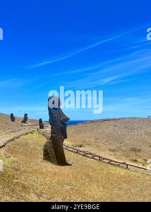 Une rangée de statues de moai à la carrière de Rano Raraku sur l'île de Pâques, au Chili, face au Pacifique sous un ciel bleu clair. C'est un site du patrimoine mondial de l'UNESCO. Banque D'Images