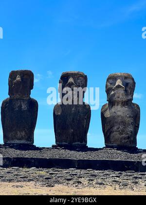 Trois majestueuses statues de moai se dressent sur l'île de Pâques, au Chili, sous un ciel bleu clair. Ces sculptures anciennes reflètent l'héritage culturel du Rapa Nui Banque D'Images