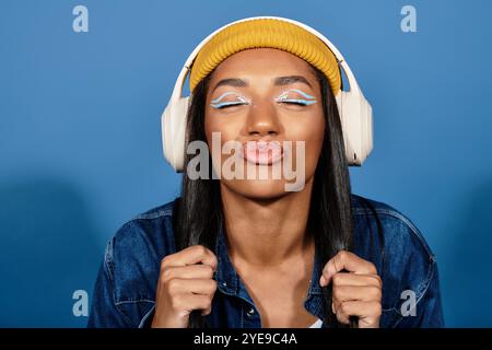 Une jeune femme élégante pose de manière ludique, mettant en valeur sa tenue chaude et son maquillage bleu vif. Banque D'Images