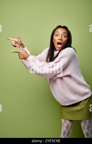 Une jeune femme présente sa tenue d'automne élégante tout en faisant des gestes ludiques avec excitation. Banque D'Images