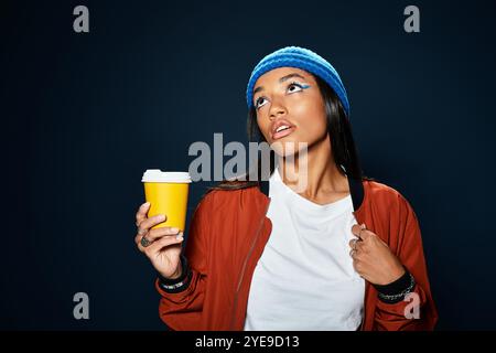 La jeune femme présente avec confiance sa mode automnale chaude tout en sirotant un café. Banque D'Images
