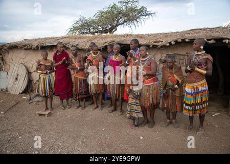 Les femmes et les enfants Datoga chantent en saluant les touristes devant leur maison de boue près du lac Eyasi, Tanzanie ; Tanzanie Banque D'Images