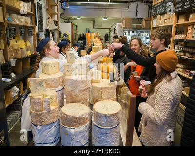 Clients dégustant du fromage à la boutique Neal's Yard Dairy à Borough Market, Londres, Royaume-Uni ; Londres, Angleterre Banque D'Images