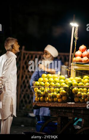 Homme vendant des produits frais dans la rue la nuit dans la ville d'Amritsar, Inde ; Amritsar, Punjab, Inde Banque D'Images